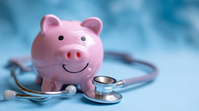 Pink piggy bank with a stethoscope symbolizing saving money on healthcare costs