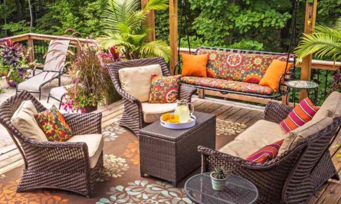 A cozy patio with wicker furniture, floral cushions, and orange pillows