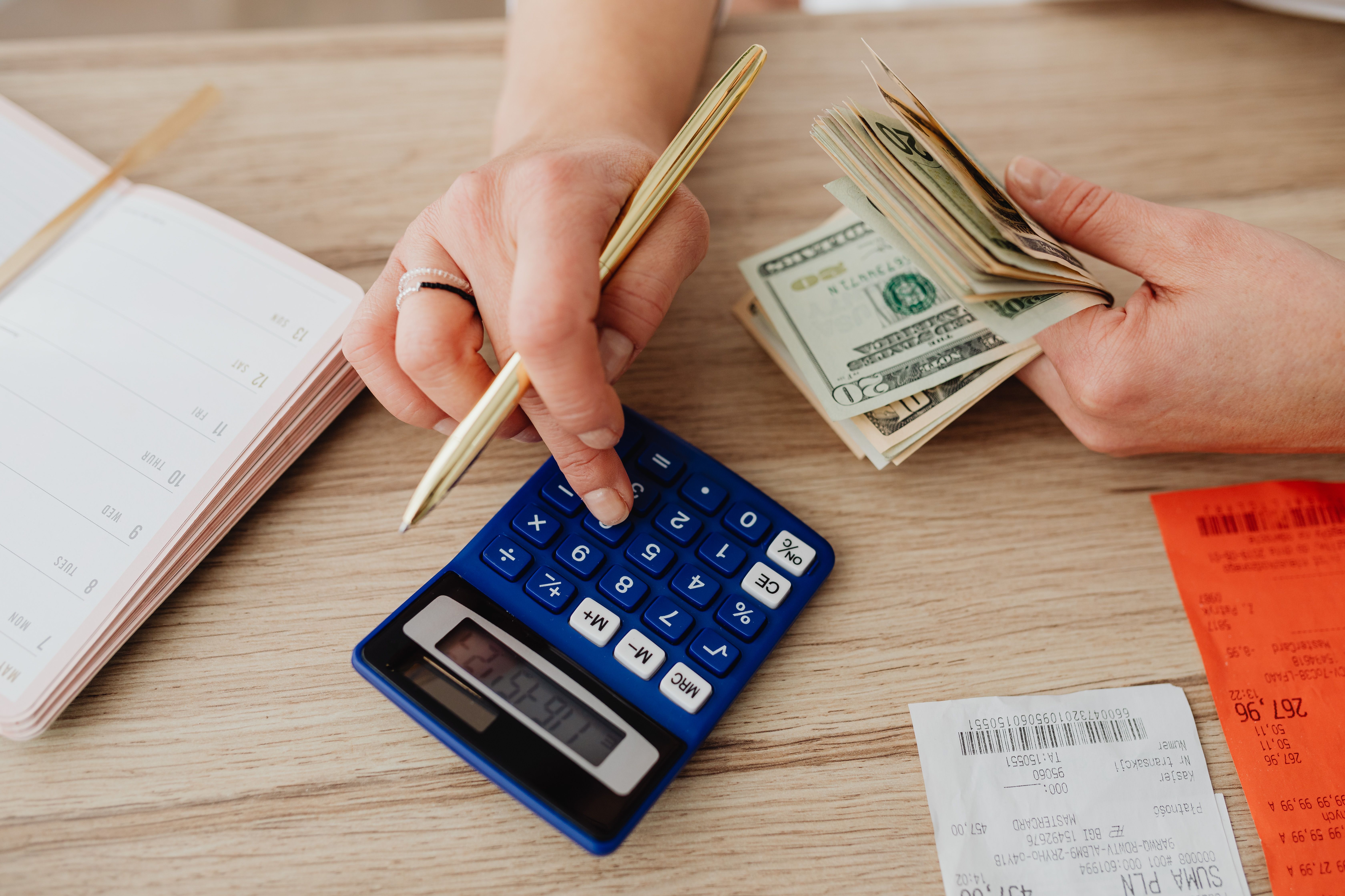 Hands counting cash next to a calculator, symbolizing setting a budget for online gaming