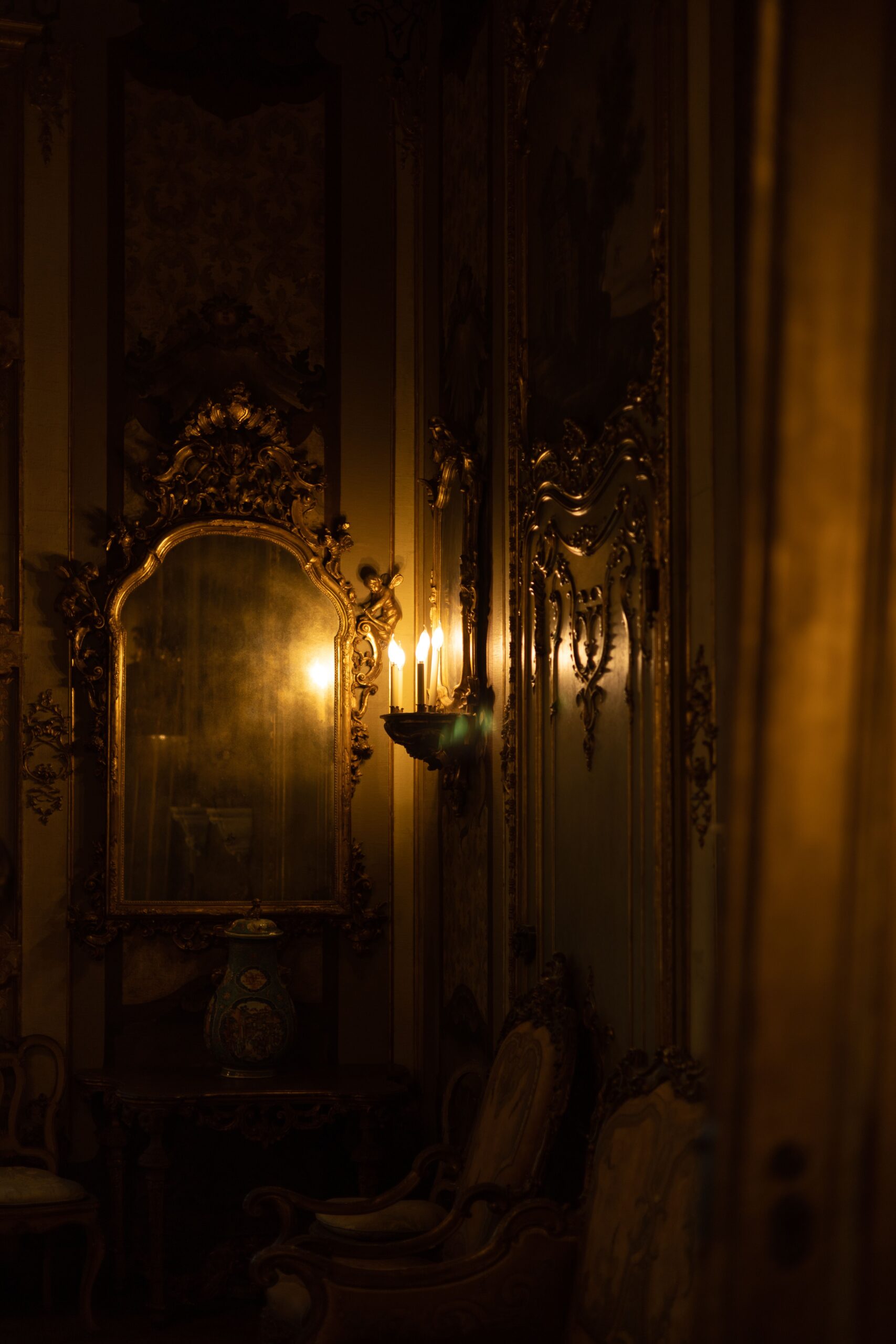 Elegant antique room with ornate mirror and candlelight, creating a warm and vintage ambiance