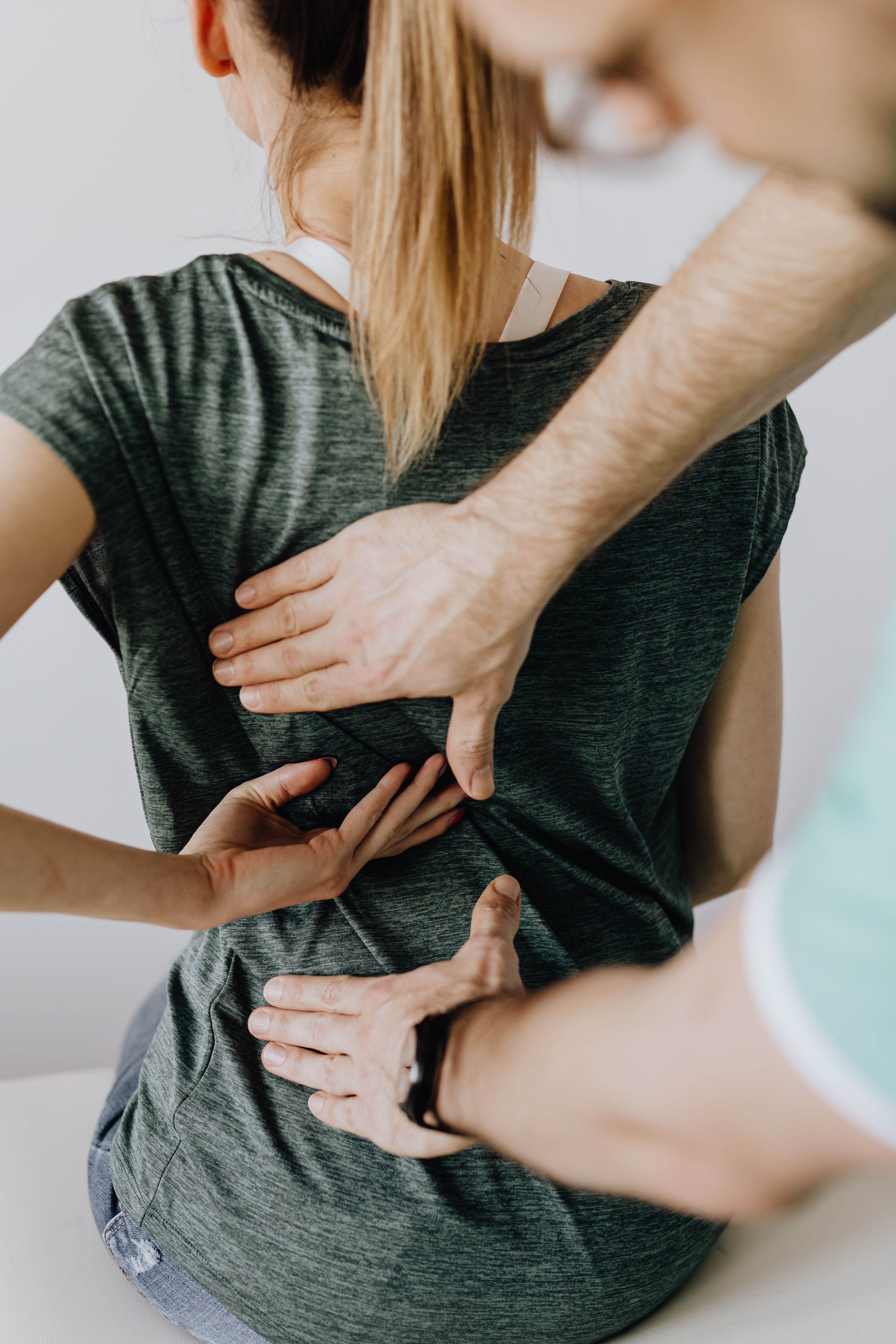 Chiropractor examining a patient's back pain point during a clinical assessment