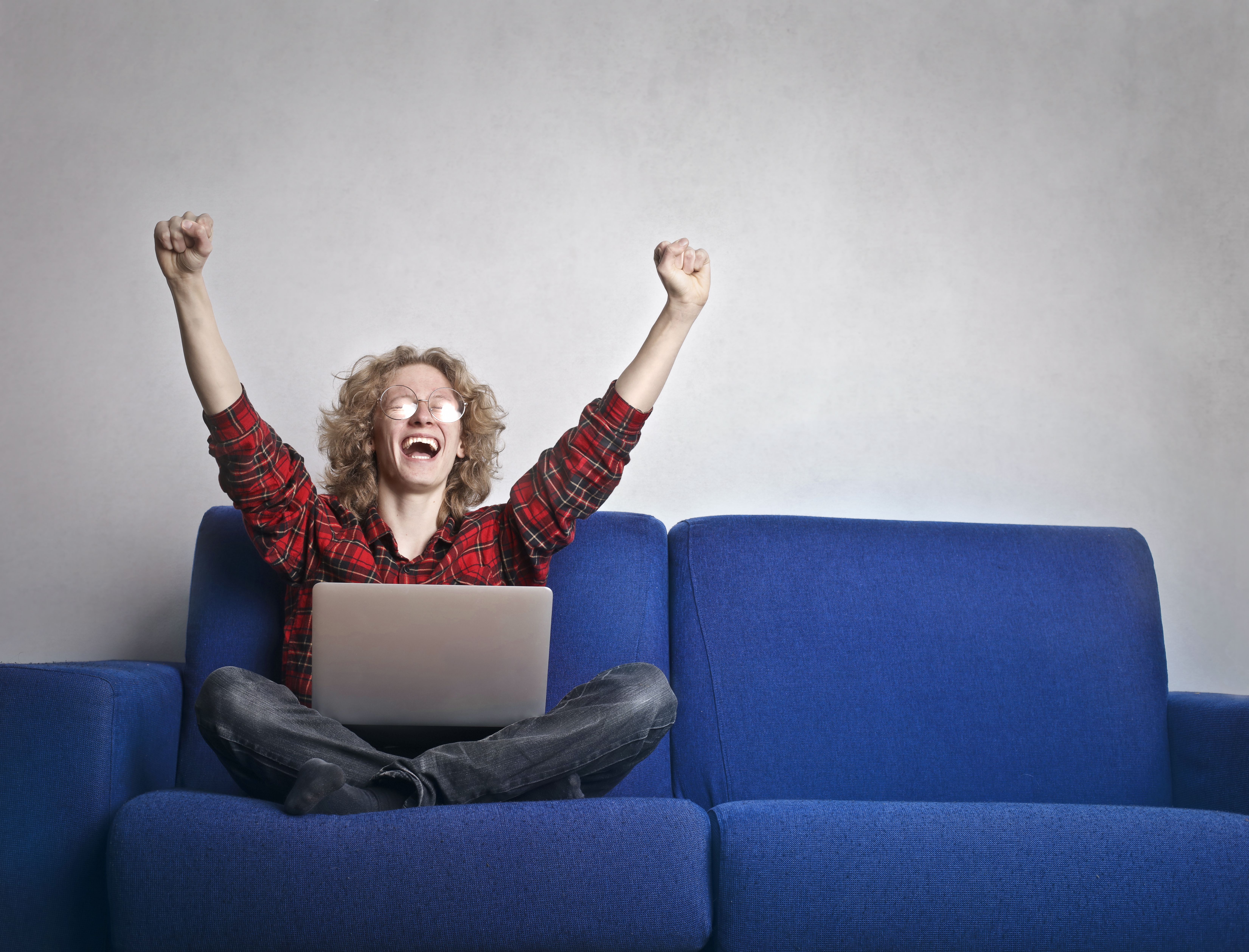 Person celebrating a win while using a laptop, capturing the thrill of cashing out in a crash game