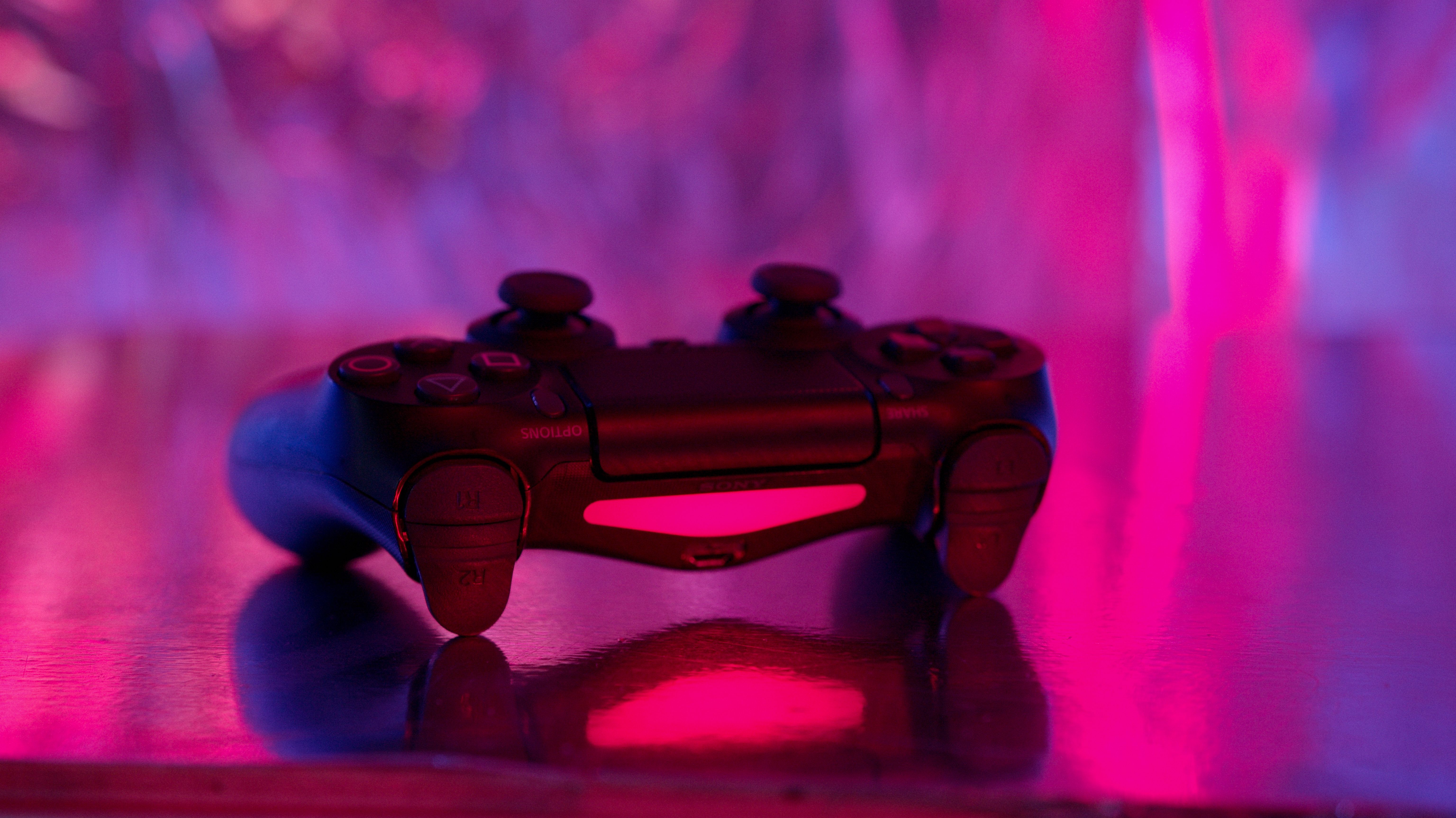 Wireless game controller lit by vibrant pink and purple neon lights
