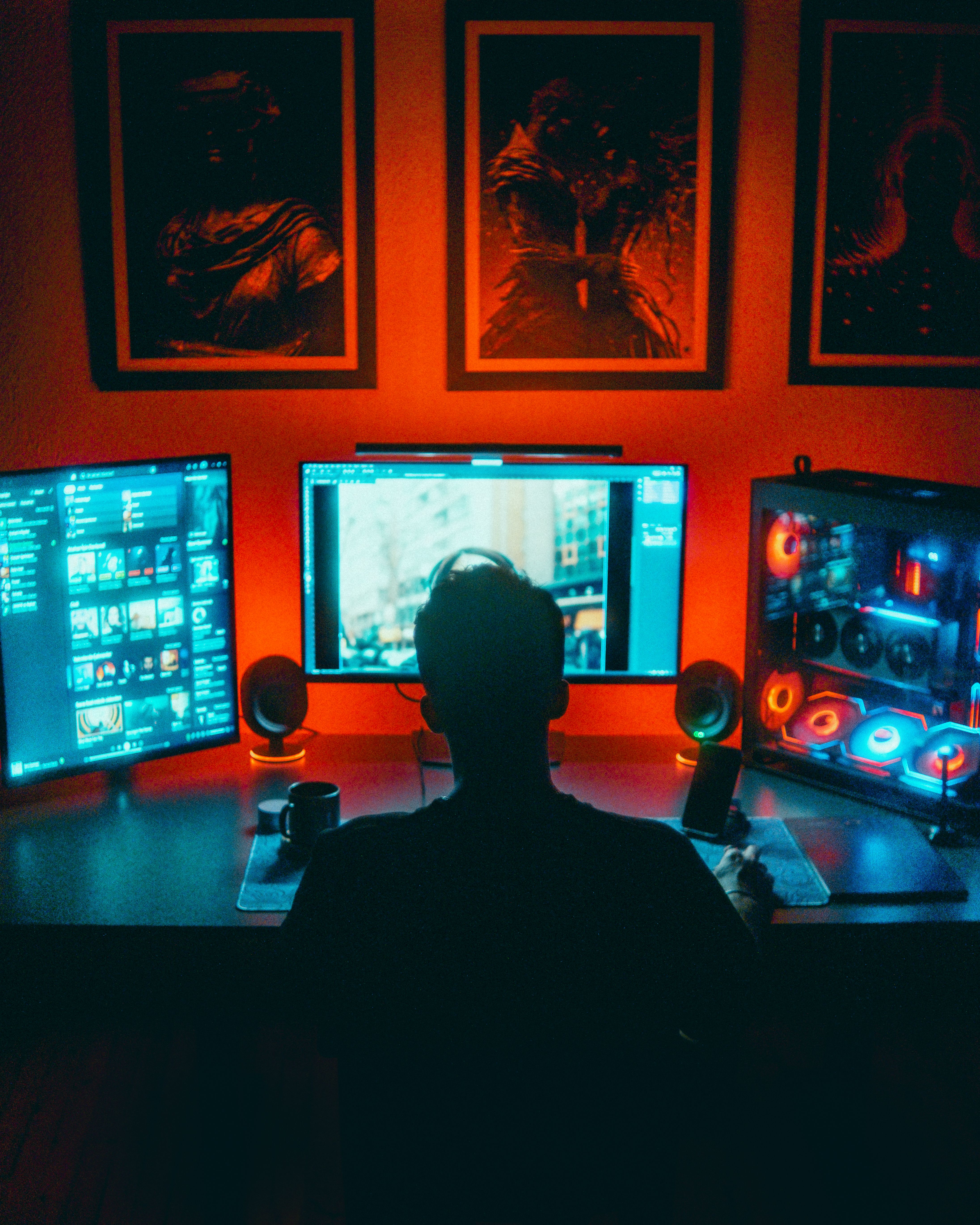 Silhouette of a gamer at a dual monitor setup lit by neon lights