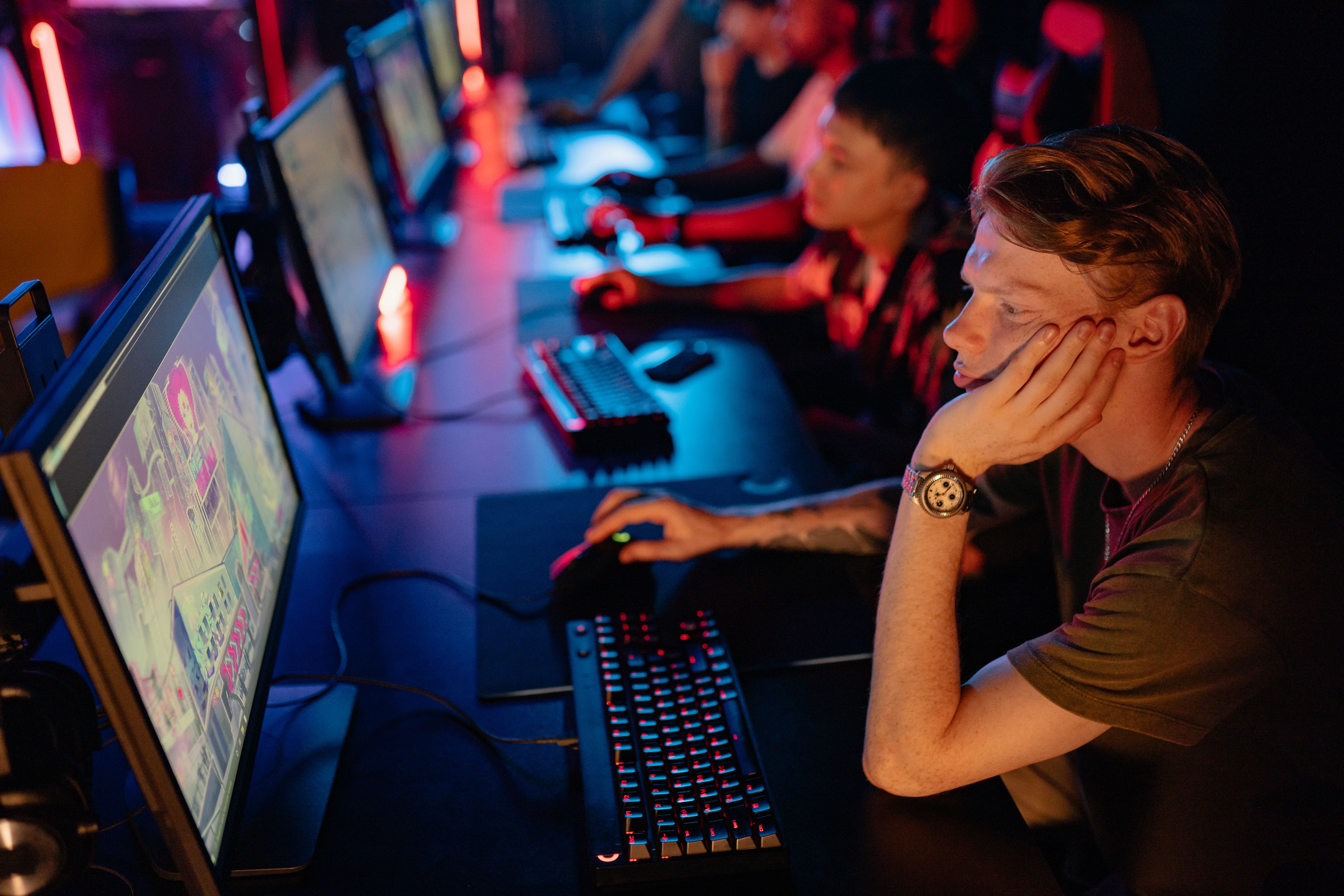 Gamers intensely focused on an online esports competition in a dimly lit arena