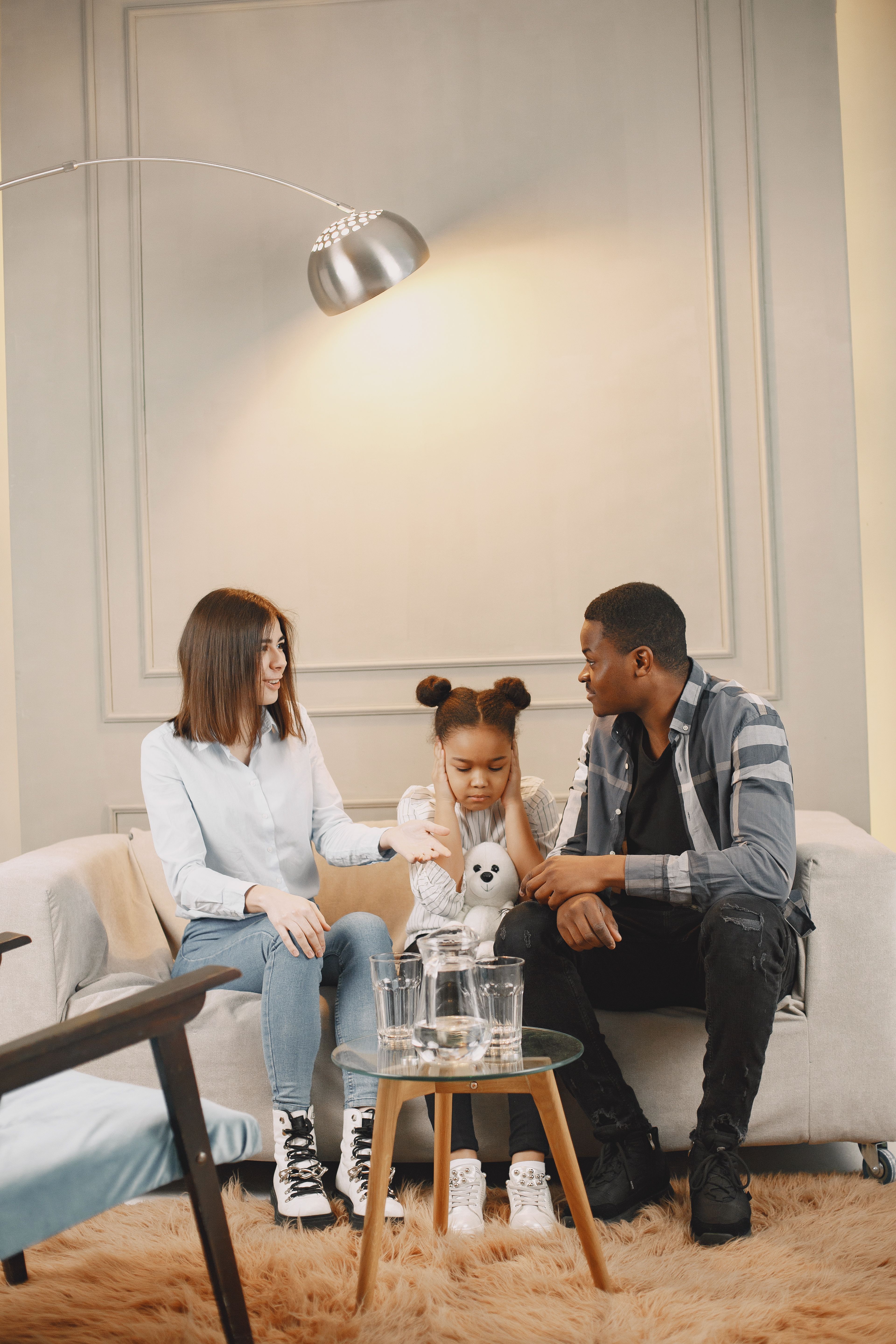 A family having a supportive, thoughtful conversation together on a sofa at home