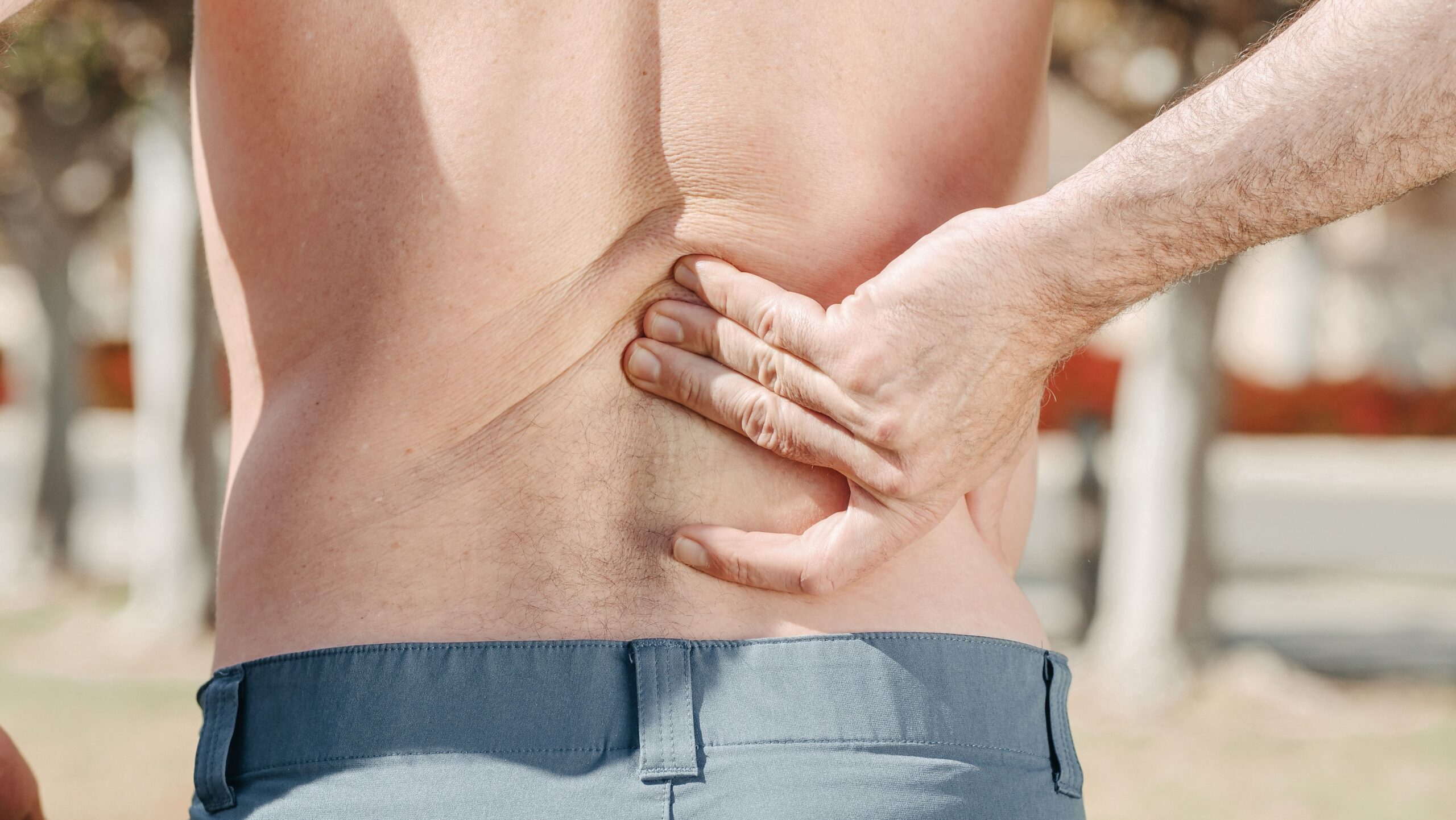 Close-up of a man holding his lower back in pain, indicating recurring discomfort