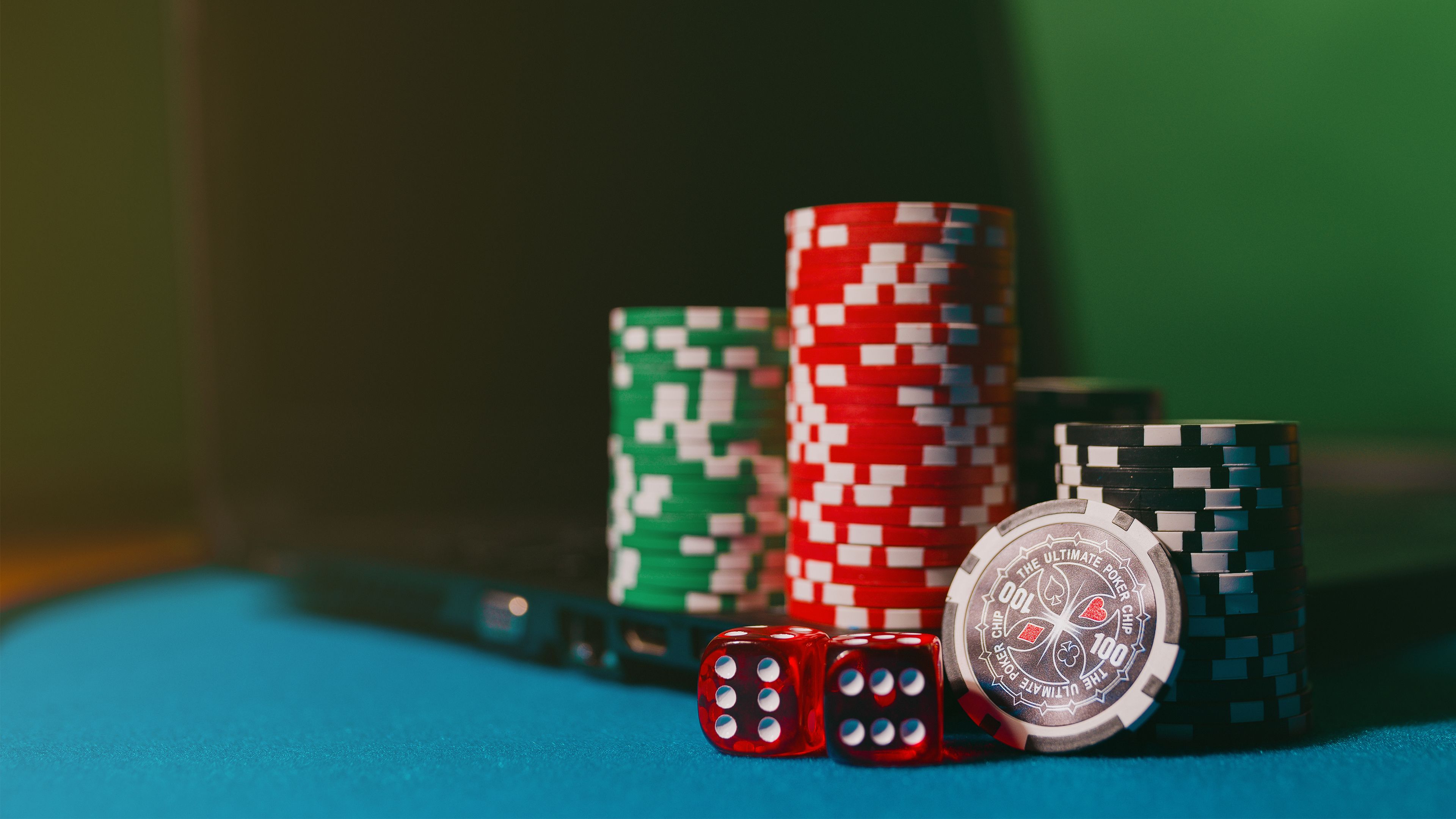Casino chips and dice on a felt table next to a laptop, symbolizing the shift to online casino gambling
