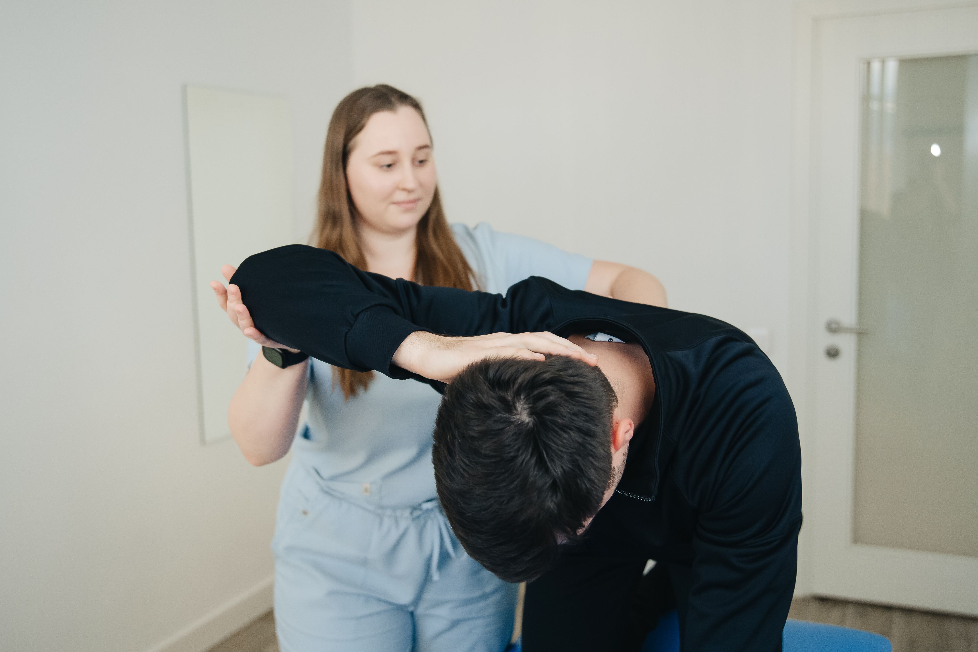 Physiotherapist assisting a patient with a stretching exercise for back rehabilitation