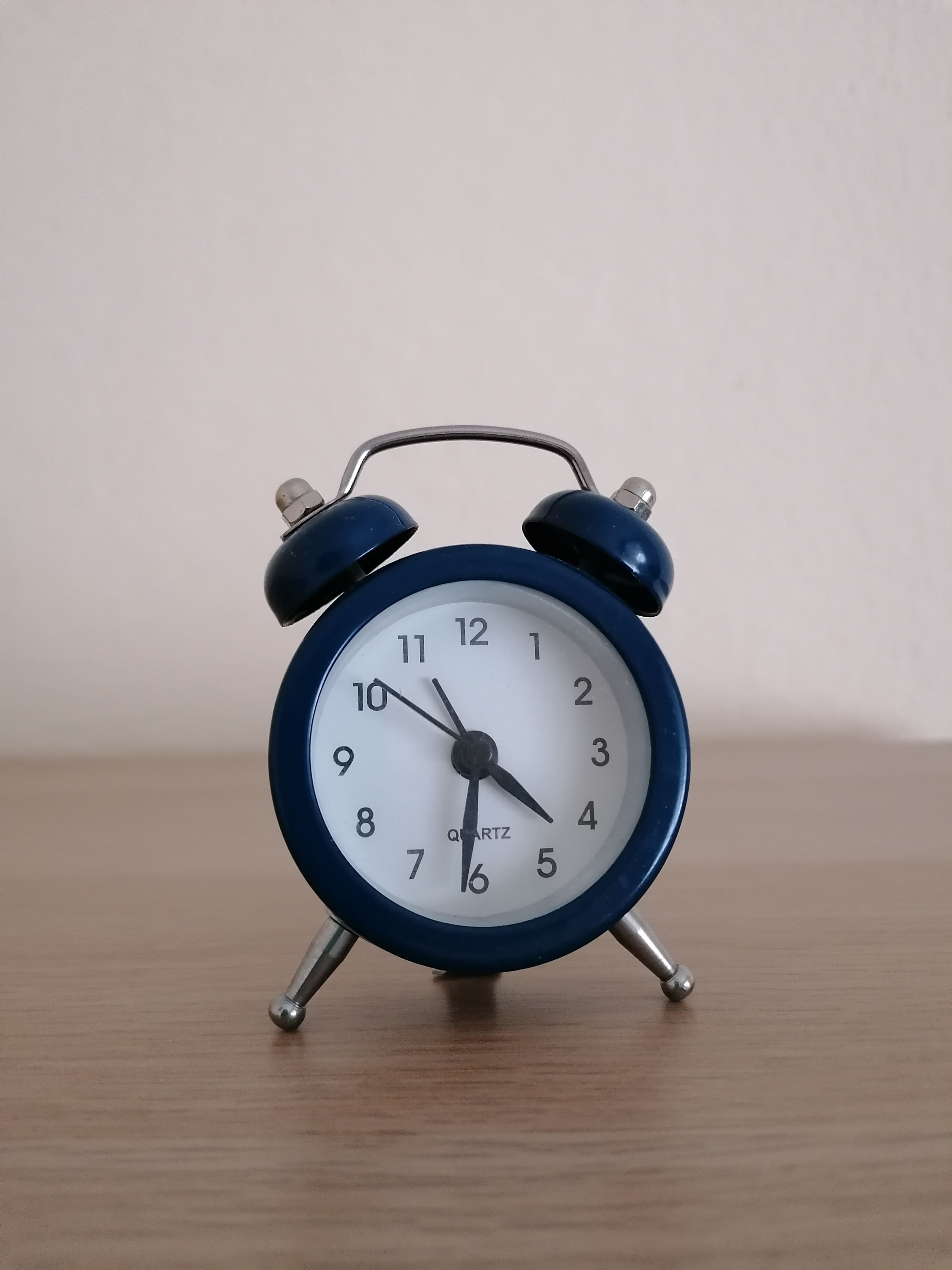 Classic blue analog alarm clock on a wooden table, representing setting time limits for gaming sessions