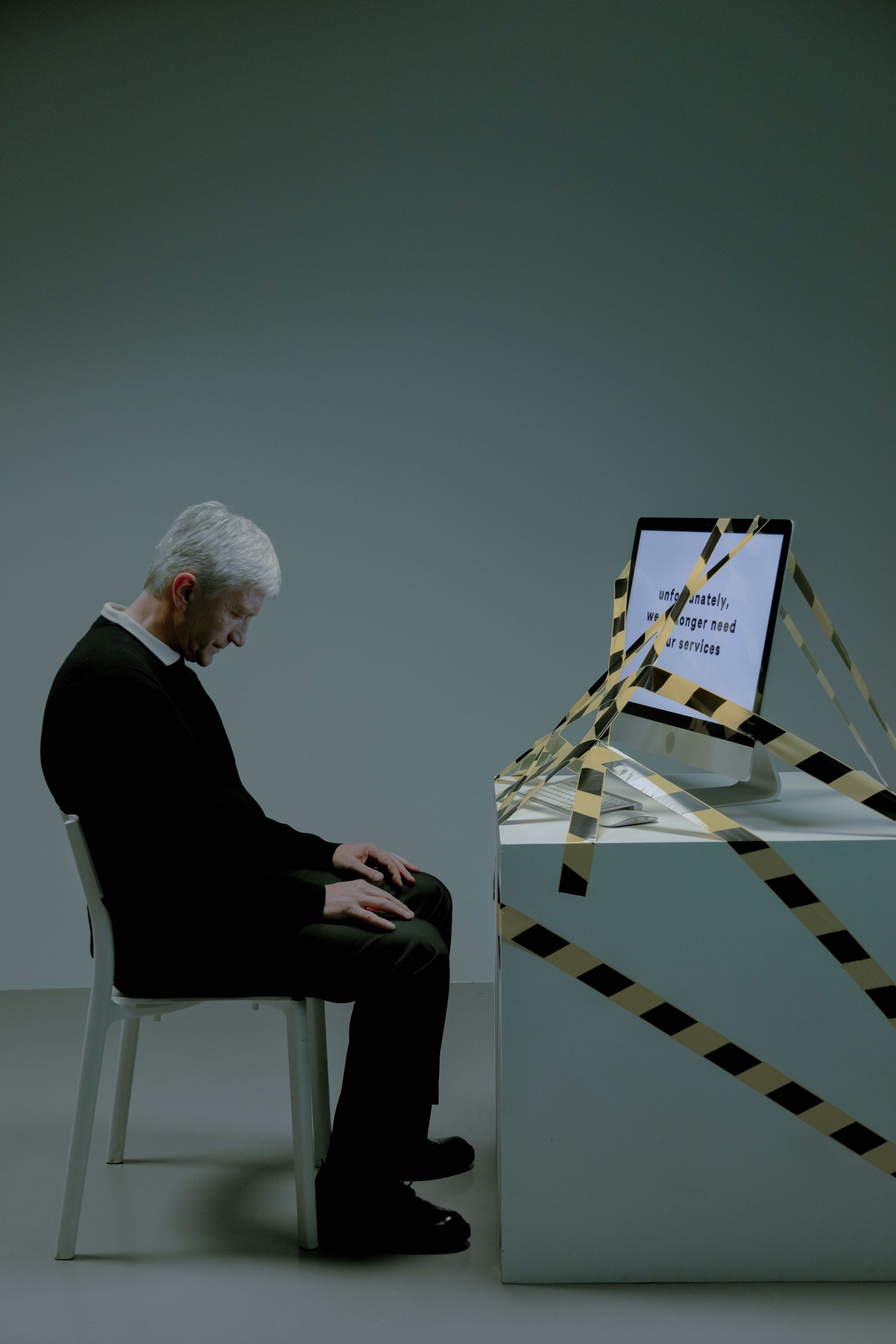 An upset man sitting beside a computer wrapped in caution tape, symbolizing warning signs of problem gambling