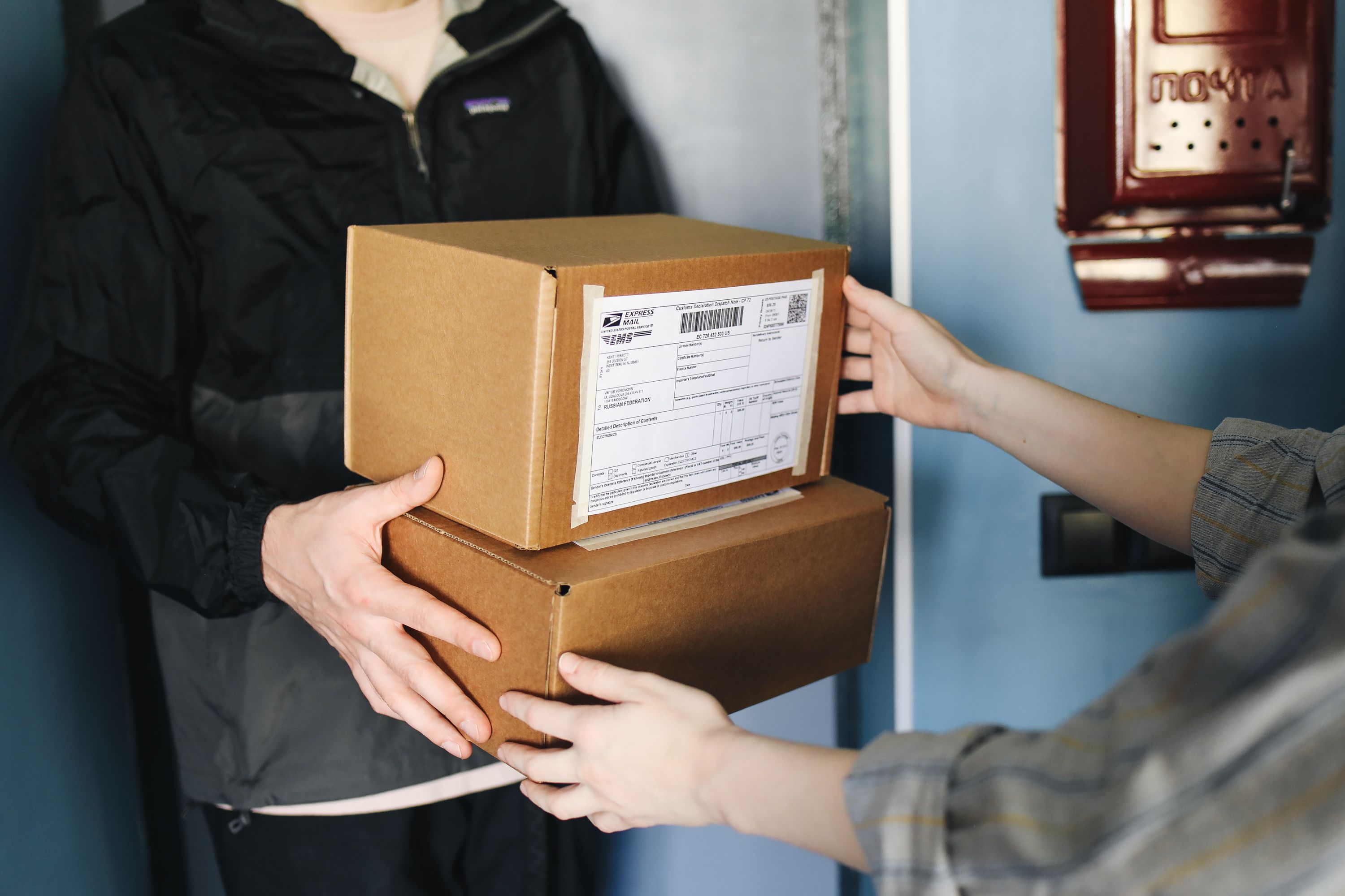 Close-up of hands exchanging bulk cardboard boxes, representing packaging delivery and logistics