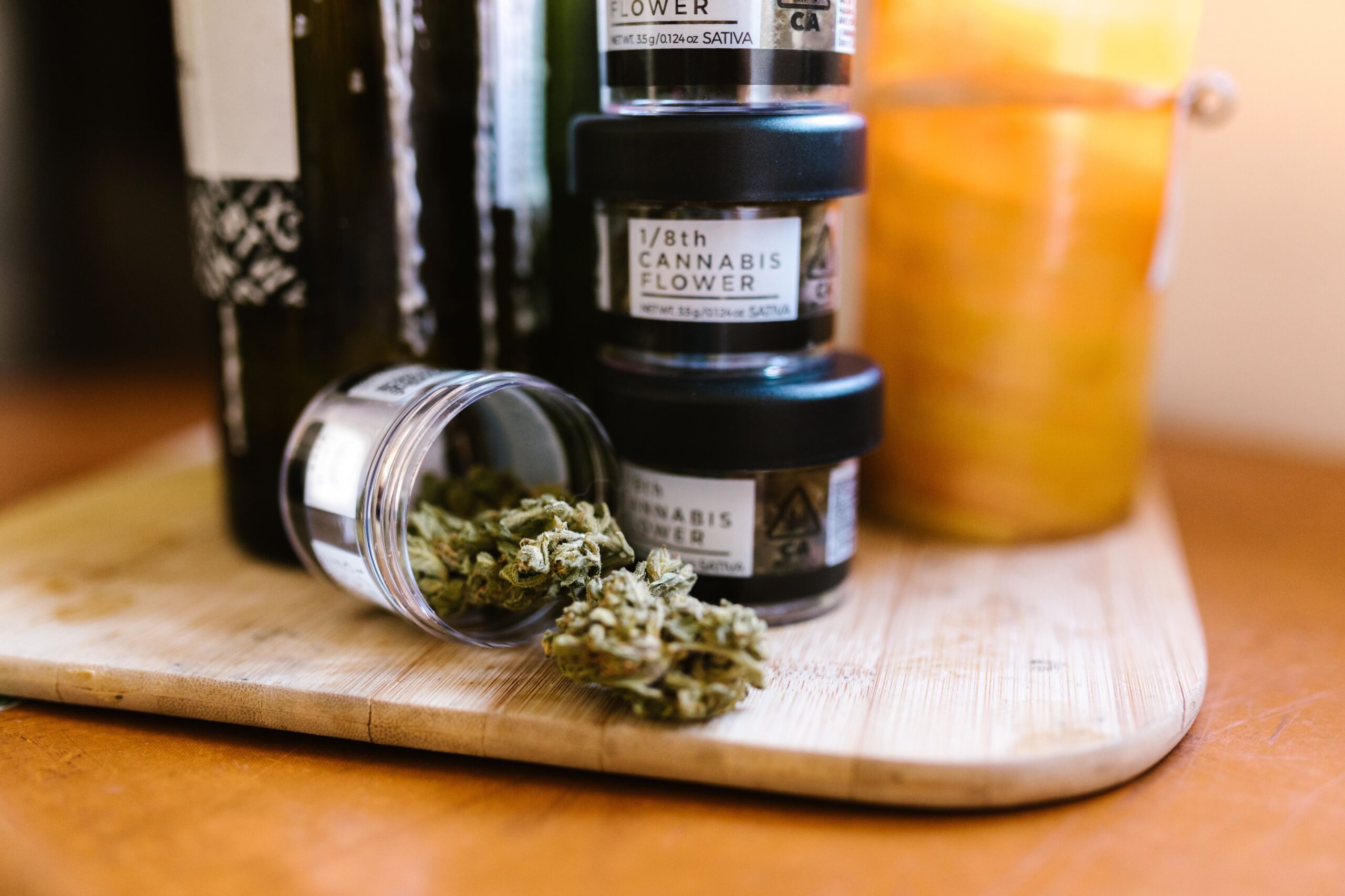 Cannabis buds displayed in glass jars on a wooden board, showing a finished packaged product