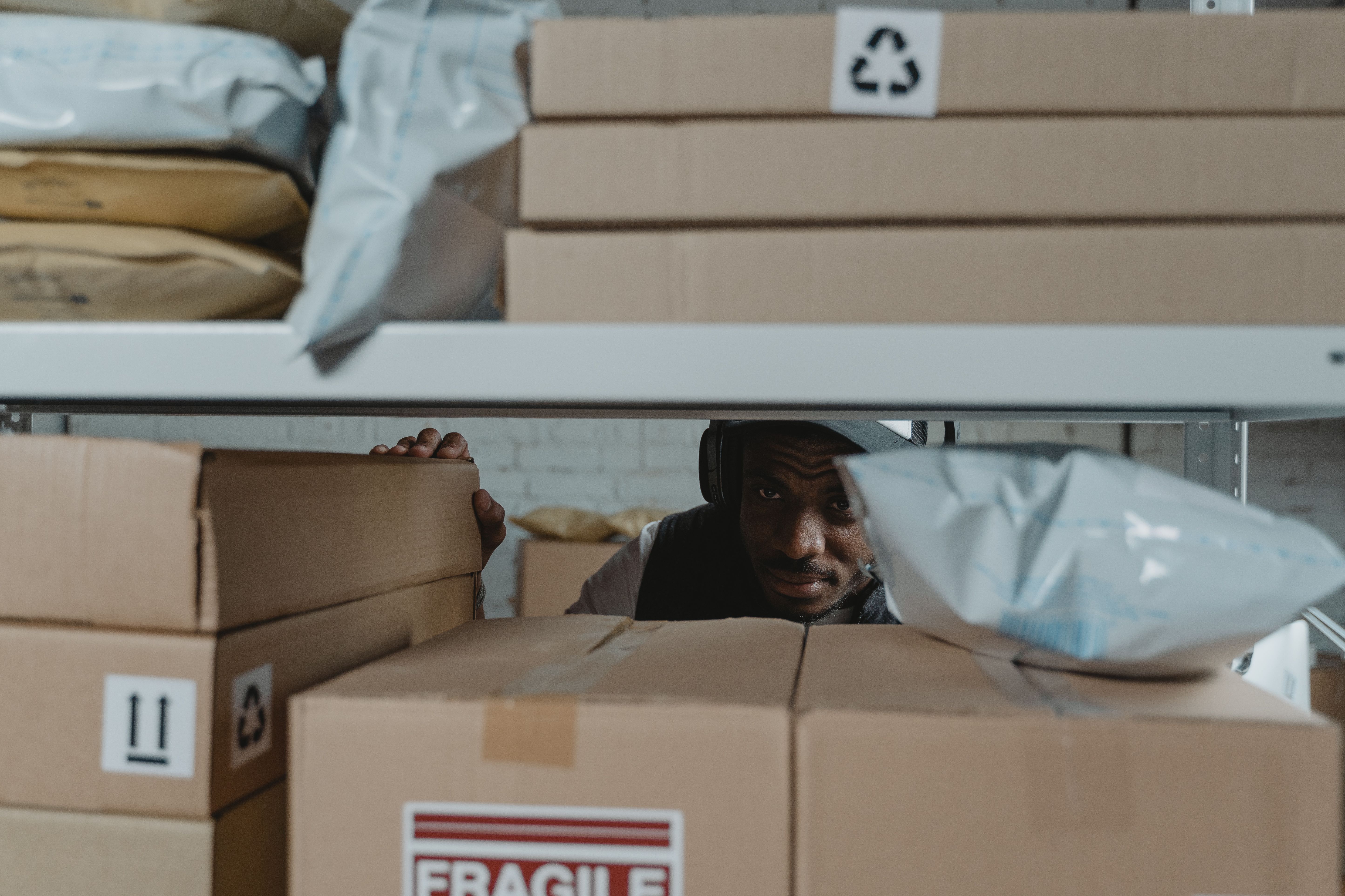 Warehouse worker inspecting packaged products on shelves to verify quality and accuracy