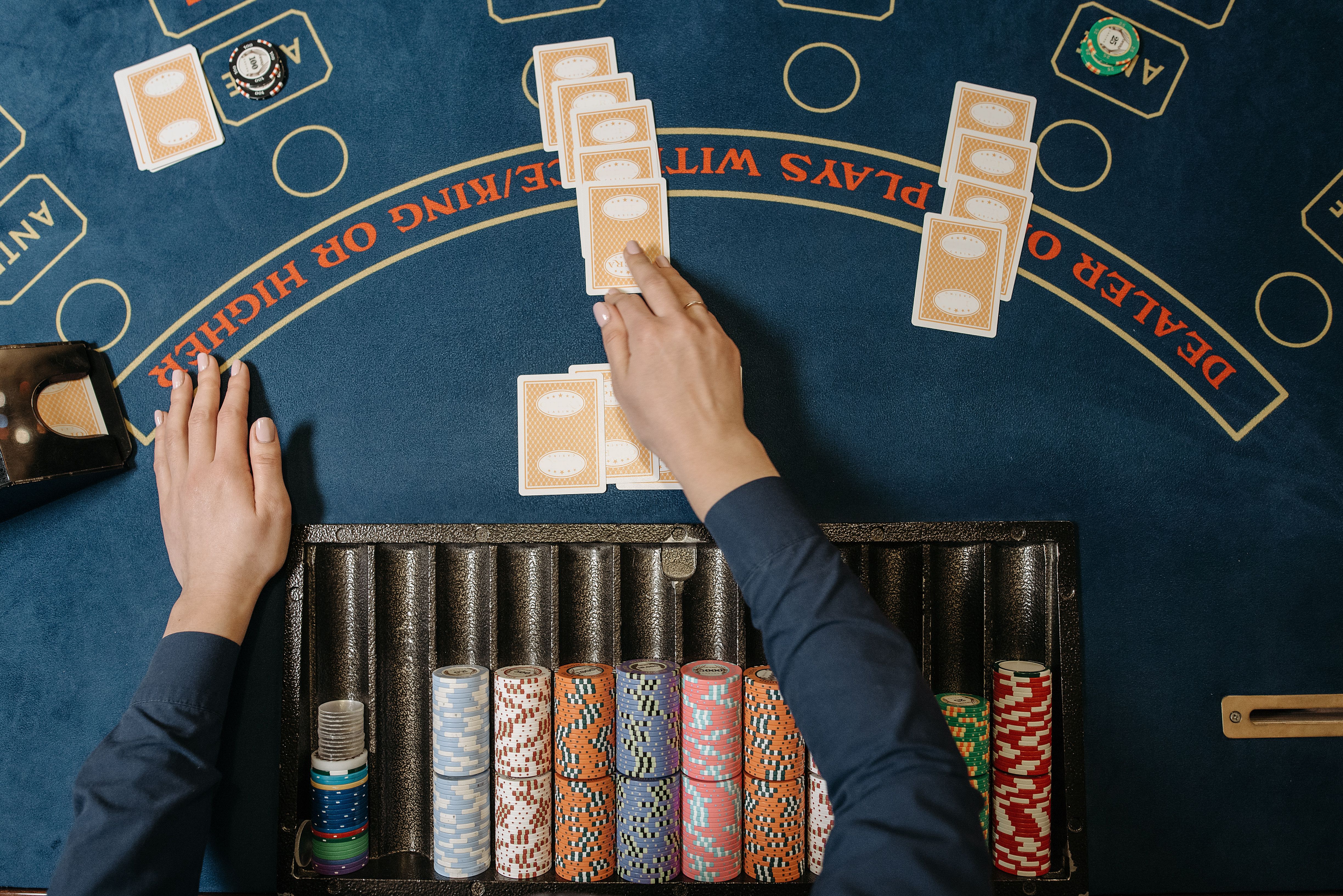 Dealer hands distributing cards at a blackjack table with chips, illustrating casino card games.