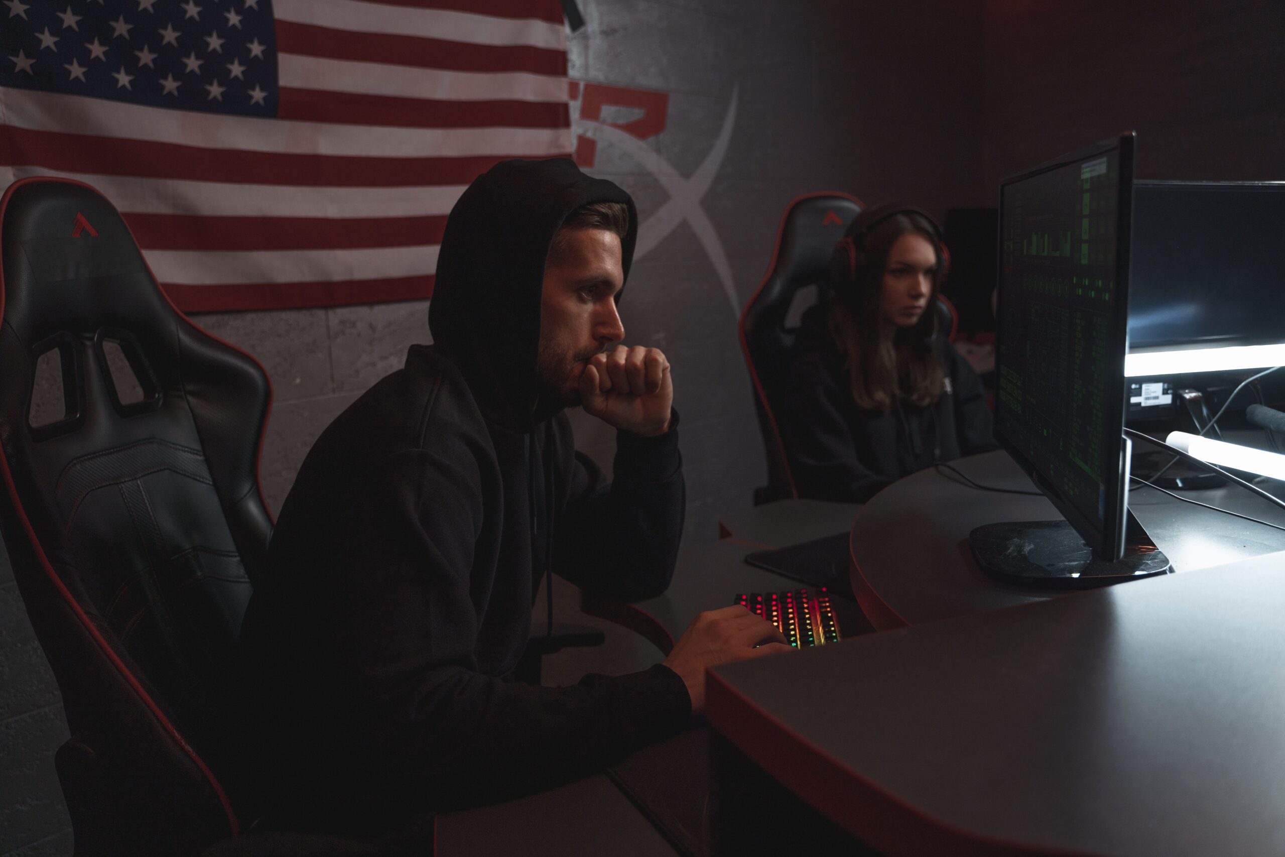 Two cybersecurity analysts reviewing threat data on monitors in a dimly lit operations setting.
